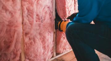 A photo of insulation being places inside a building. 