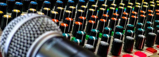 A microphone rests on a live sound mixing board