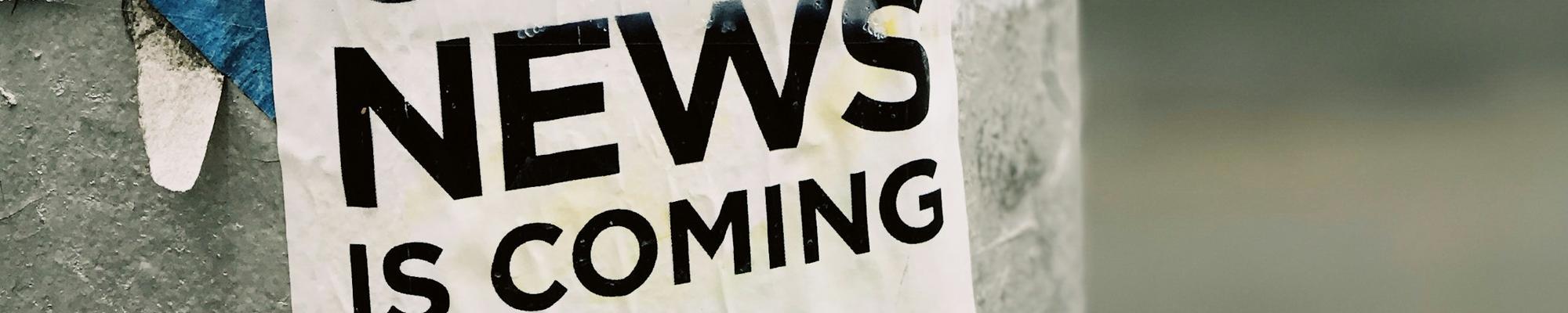 A poster on a wall saying "good news is coming"
