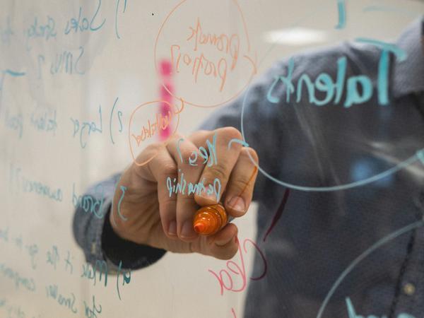 A person writing on a transparent whiteboard